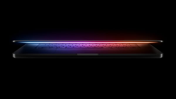 A MacBook Pro half open with a multicolor glow on a black background