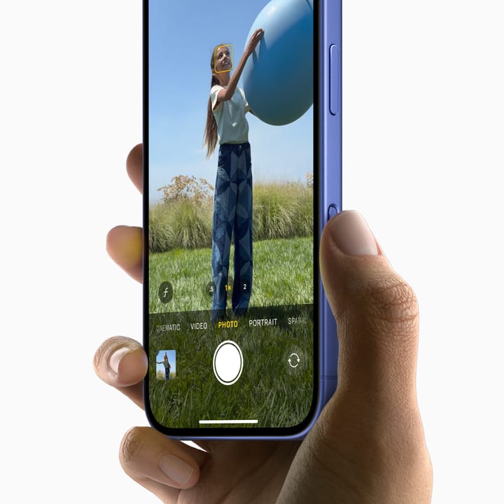 A picture of a person holding an iPhone 16, showcasing the Camera Control